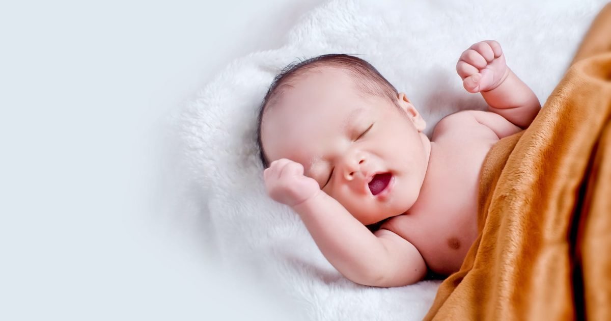 baby lying on white fur with brown blanket