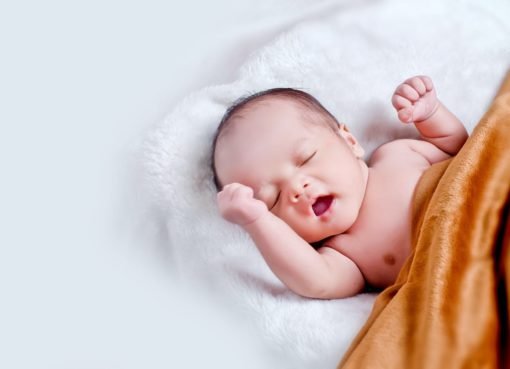 baby lying on white fur with brown blanket